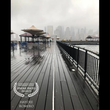 On a rainy morning, I captured a nice photo of my favorite spot at Exchange Place in Jersey City, the wooden planks of the pier drawing your eyes toward the fog-shrouded skyscrapers of Manhattan in the background.