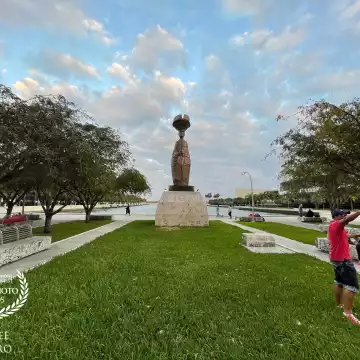 Clouds frame a statue dedicated to Flora, the Collector of Dreams, by the renowned Cuban artist Cundo Bermudez, on the waterfront Maurice A. Ferre Park in downtown Miami, where the stone benches are occupied by the homeless while city residents stroll, run, cycle or  walk their dogs along the bayfront.