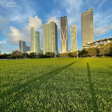 Modern skyscrapers stretch up towards clouds that appear to be racing across the sky behind the Perez Art Museum and the adjacent park in downtown Miami.