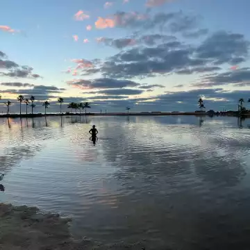 The morning sky is reflected in a wading pool at Matheson Hammock Park, in Coral Gables, south Florida, as a lone bather ventures cautiously into the water.
