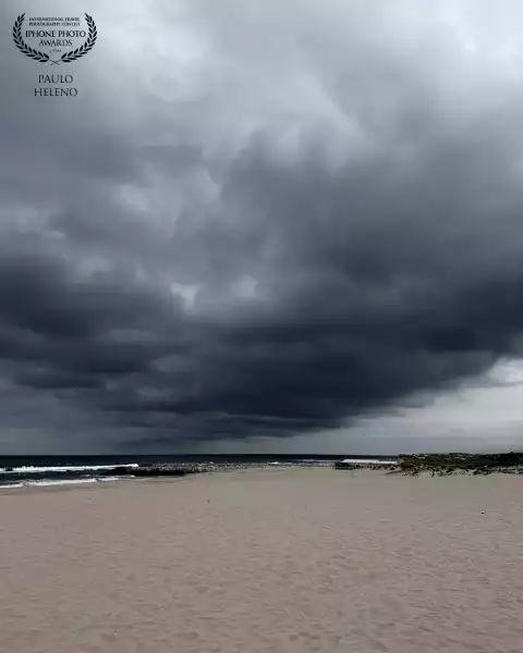Huge dark cloud lays above the beach in a very cloudy day. This way, the beach presents to us in a m...