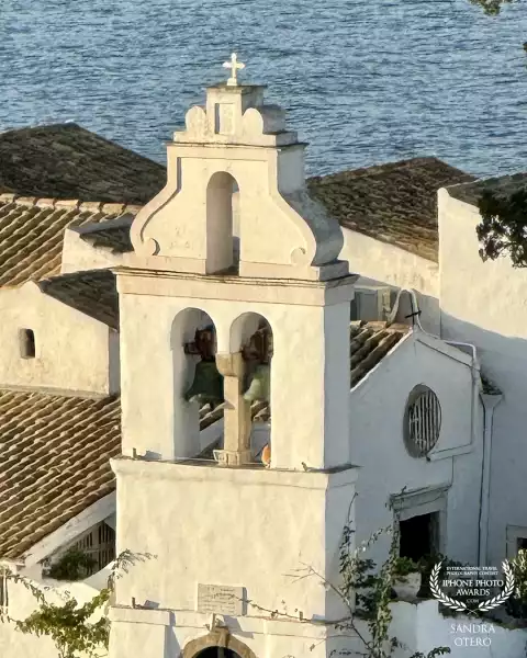Vlacherna Monastery sits on an island off the coast of Corfu, Greece. Built in the 17th century, it is distinguished by its unusual shaped, tiled roof and intense white walls that sharply contrast with the lush landscape and the brilliant blue of the sea.