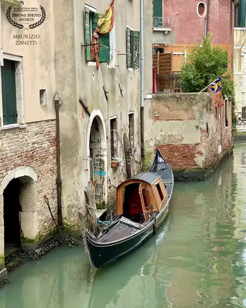 Venice, Rio de la Tetta. An old gondola moored next to the water gate of the legendary Libreria Acqua Alta.