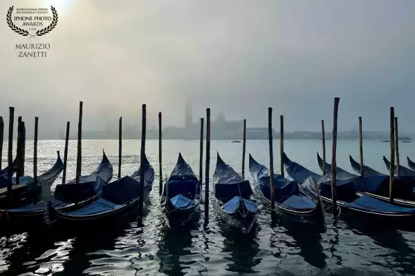 Venice. Magical moment, early in the morning, at the gondola mooring on Riva degli Schiavoni. When the fog still tries to resist the sun and hides the island of San Giorgio.