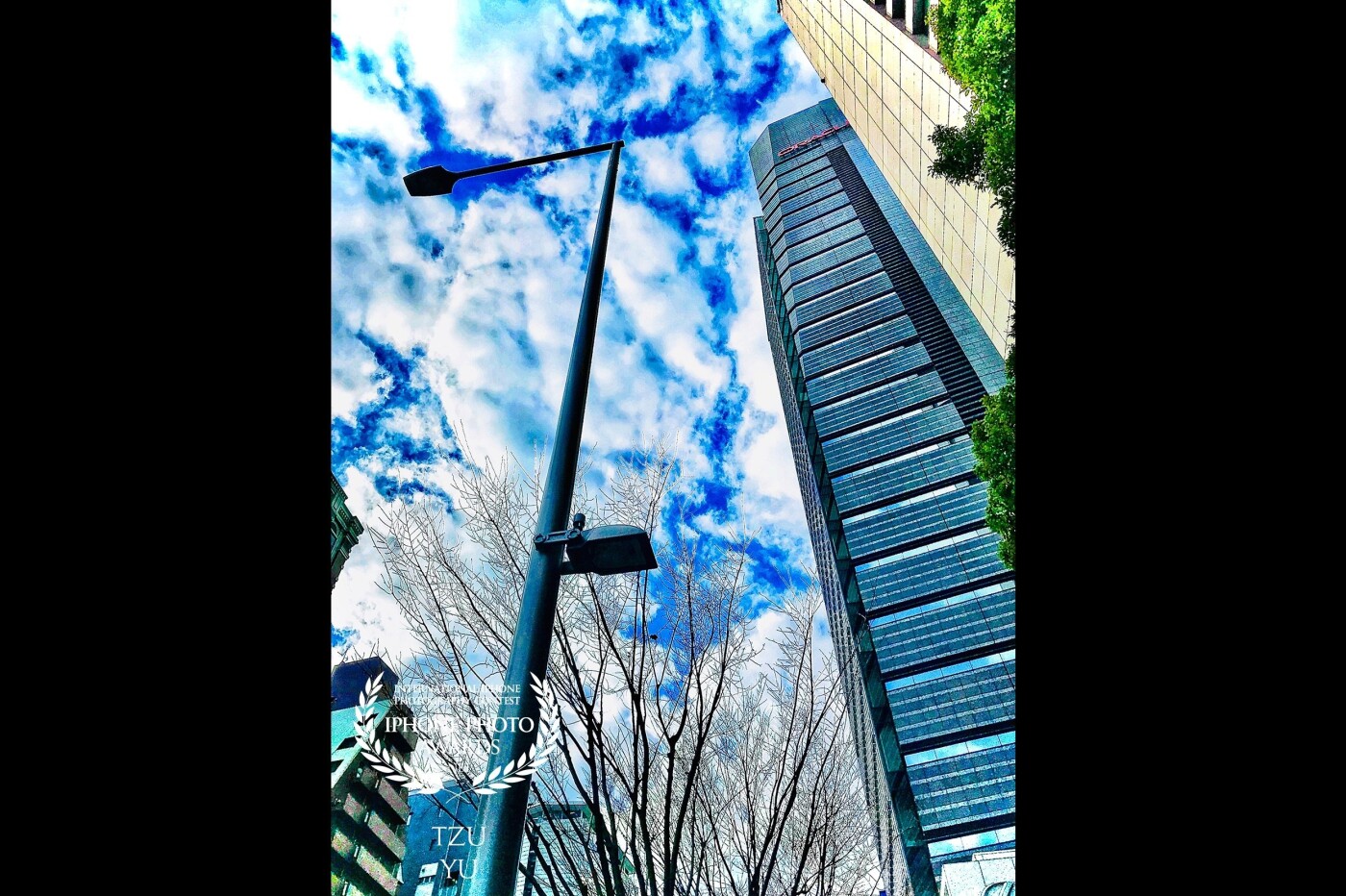 This photograph was taken on a street in Japan, overlooking the blue sky and white clouds. It feels imposing and imposing. The building reflects the white clouds, making it more dazzling and charming