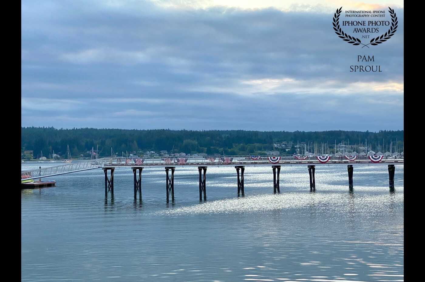 A  beautiful Pacific Northwest evening and the light on the water was a beautiful silver reflection. The light off of the water and the 4th of July flags were perfect for an iPhone 11 capture <br />
<br />
Seaside Reflections -“2021”