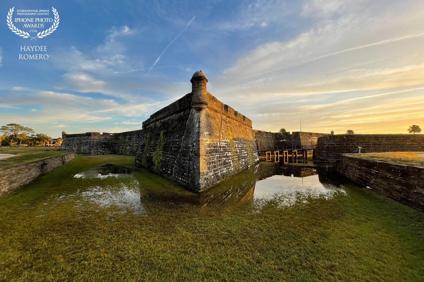 The creeping dusk sends colors across the sky and shadows over the swallow waters of the moat of the Castillo de San Marcos fort in St Augustine, Florida.