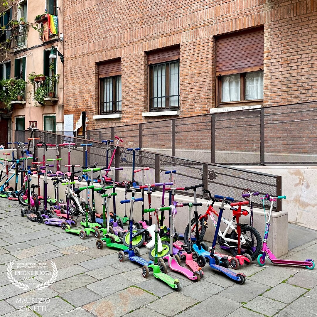 In front of a kindergarten in splendid Venice. Scooters are starting to be seen even in its centuries-old streets. The small, beautiful, push-action ones, driven by children. Who diligently park them in front of the school.