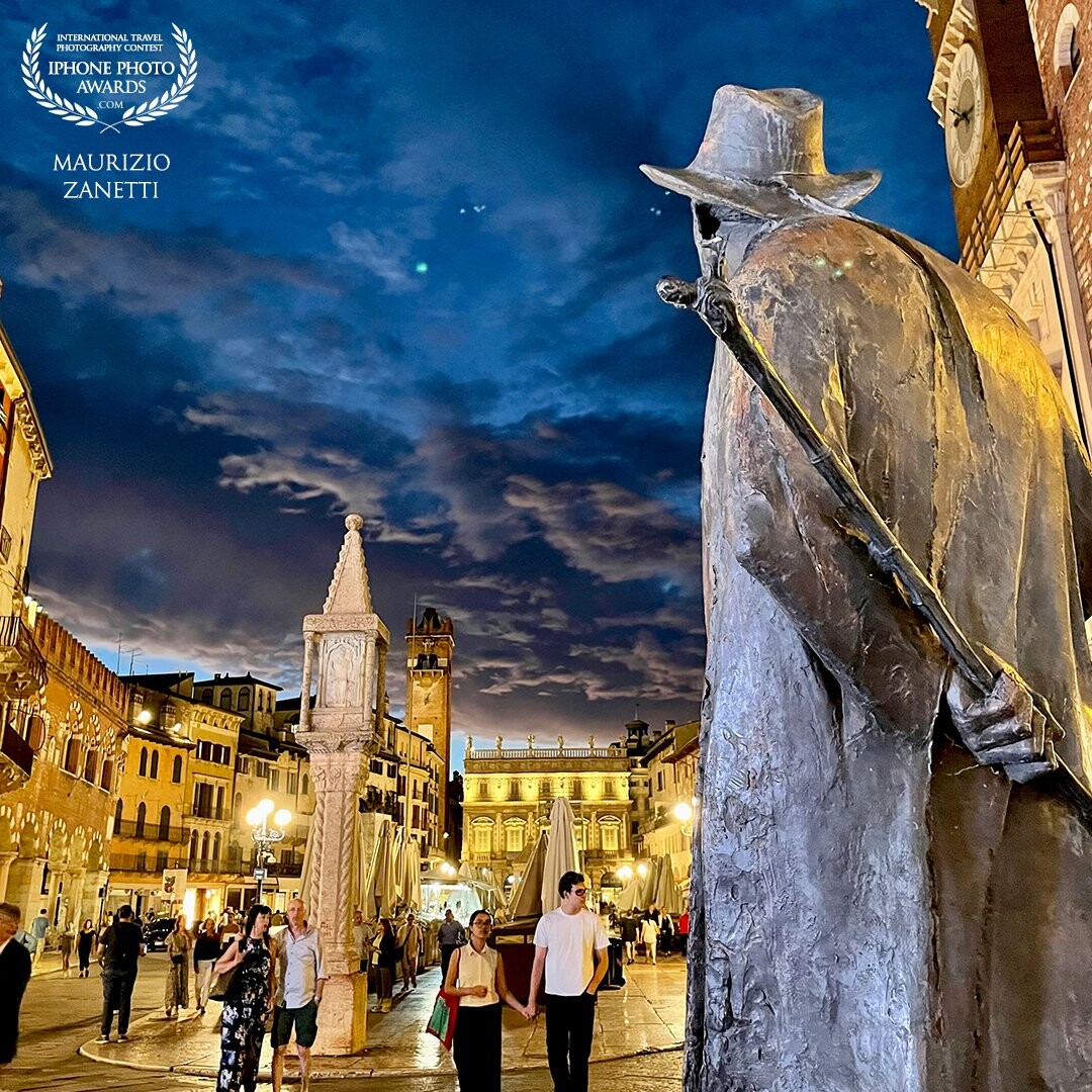 Verona, piazza delle Erbe in the evening. The warm lights, the statue of the poet Berto Barbarani (author the sculptor Novello Finotti), a storm coming.