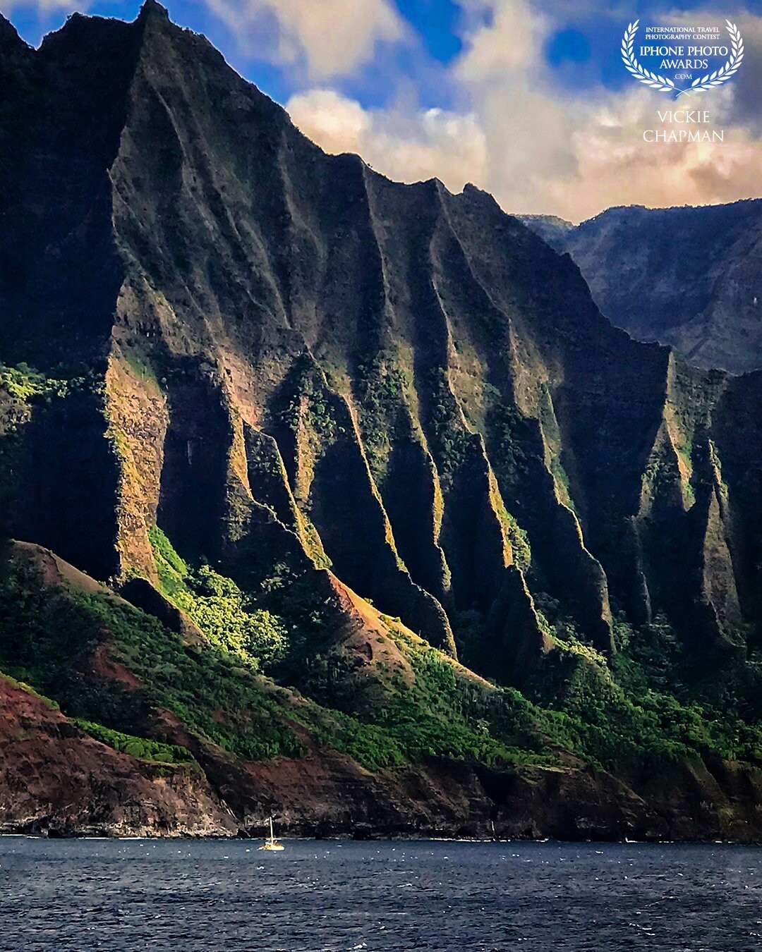 Island Magic<br />
This photo was captured as the cruise ship I was on, was passing the island of Kauai, HI. The island at this angle was fairly nondescript and unimpressive until the setting sun hit it just right. Then it was jaw dropping. It was amazing to watch the light show unfold before my eyes. The photo was made with my iPhone 11Pro Max from a moving boat and hand held!