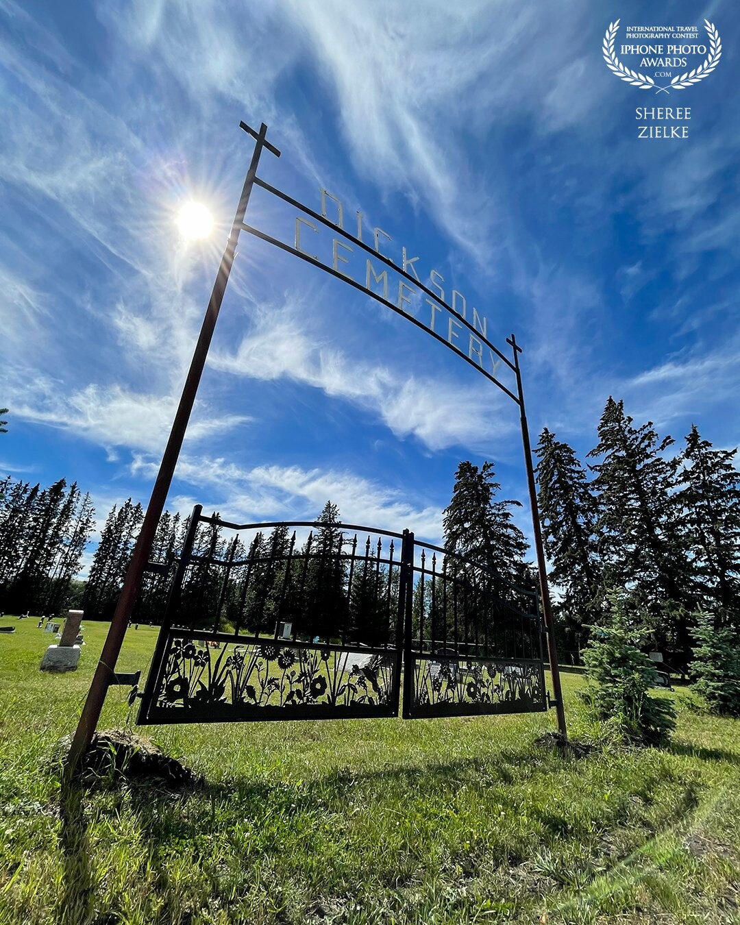 Three of my photo loves in one shot: a cemetery, a skewed view, and a sun star in a deep blue sky accented with wispy white clouds. Shot in Alberta, Canada.