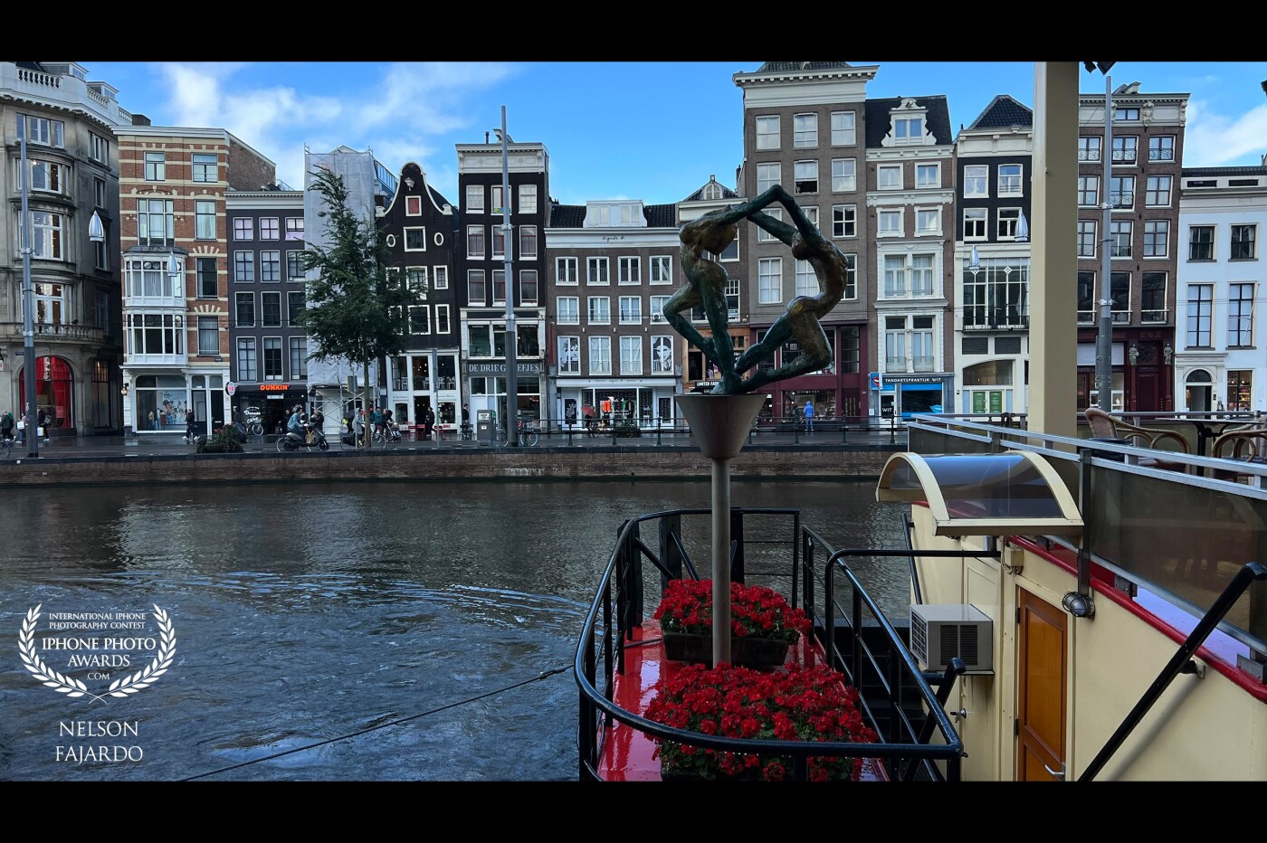 Amsterdam’s dancing lady houses and a dancing ladies sculpture art work located by the river fronting a museum and a river boat ride.