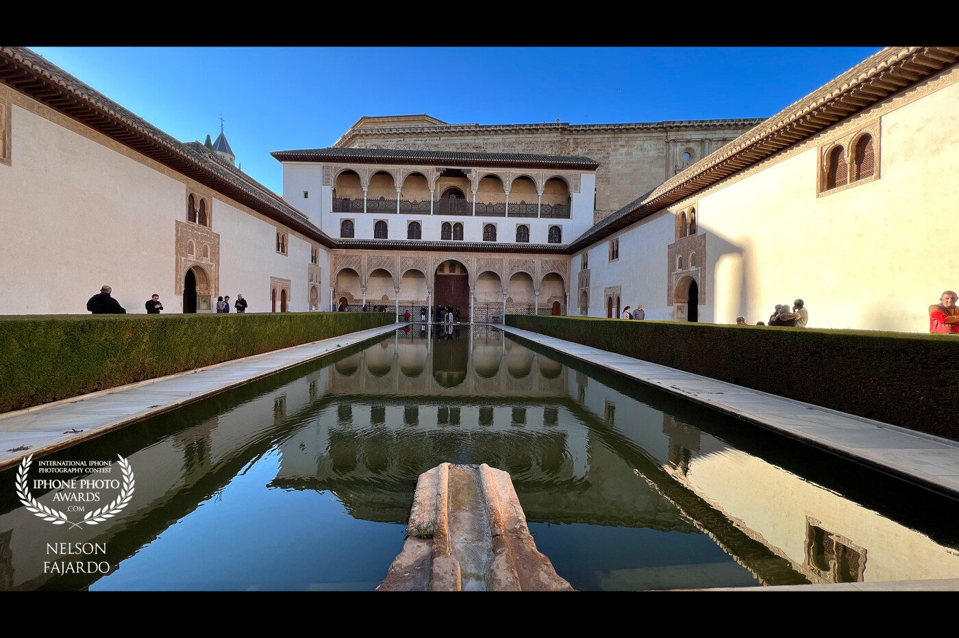A reflection of the inner palace section in Alhambra, Spain with bright sunlight and clear sky.