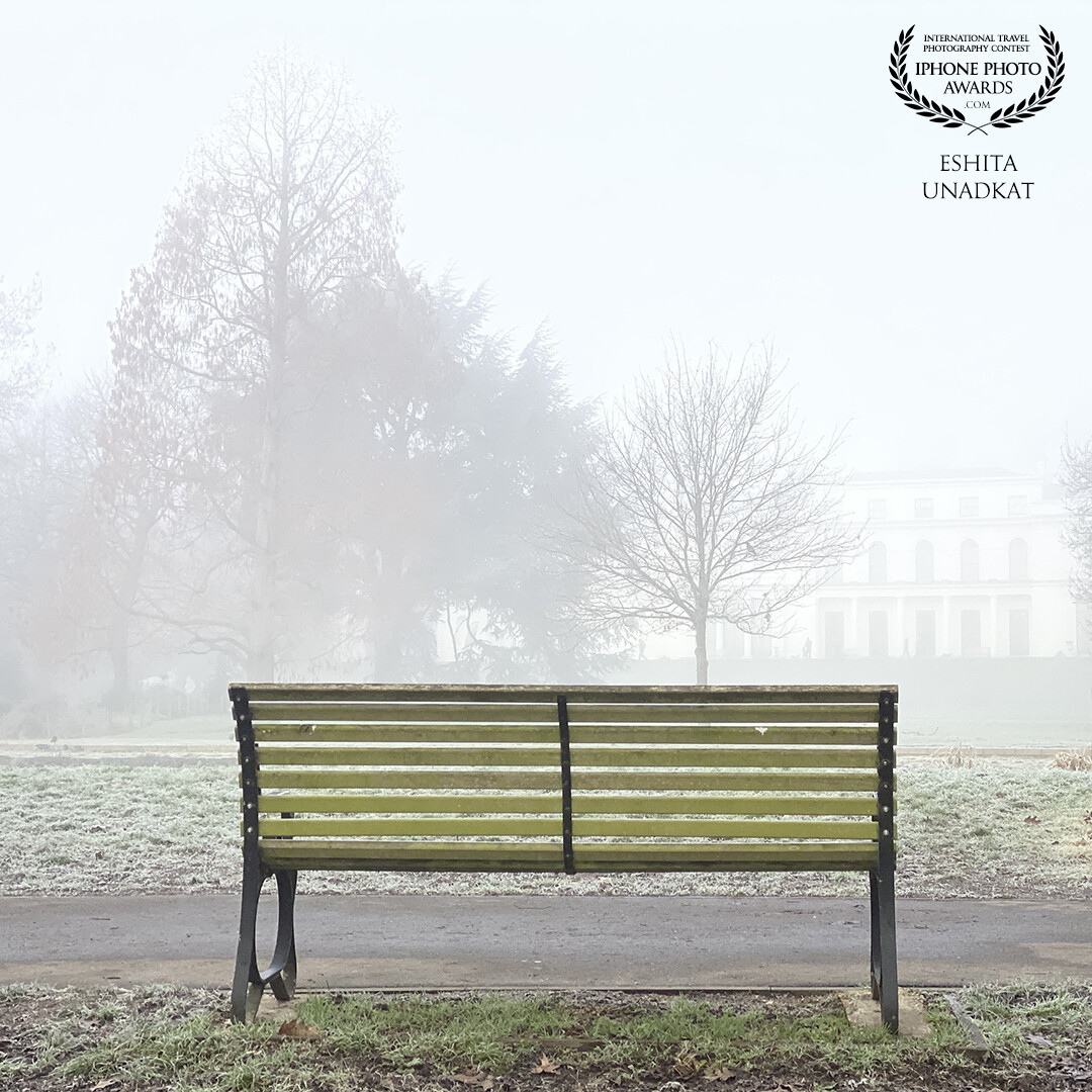 A bench with a foggy view of trees and a mansion house. <br />
Misty morning!