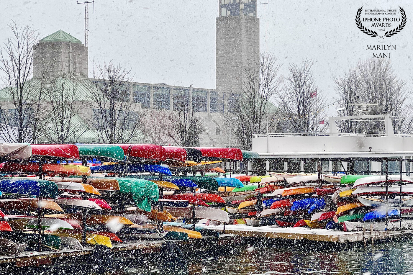A moment from a beautifully confusing spring day! While on a walk on a spring day hoping for warmer weather I was surprised by the snowfall. The snow acts like a veil covering the colourful canoes ready for summer.