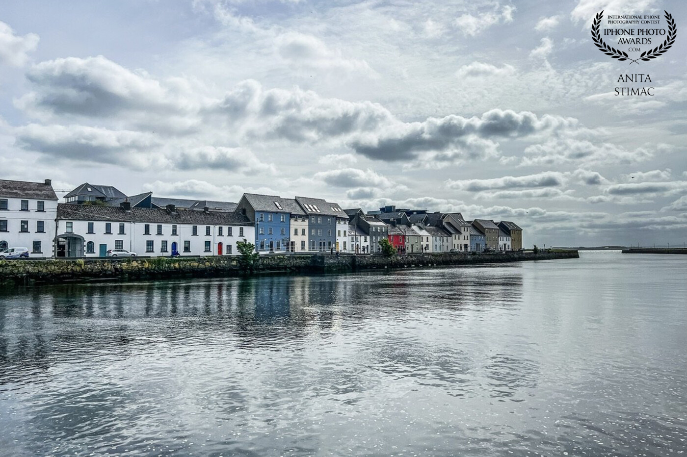 White clouds float above this picturesque city, while the ocean in the background beckons for adventure and discovery. Galway, Ireland.