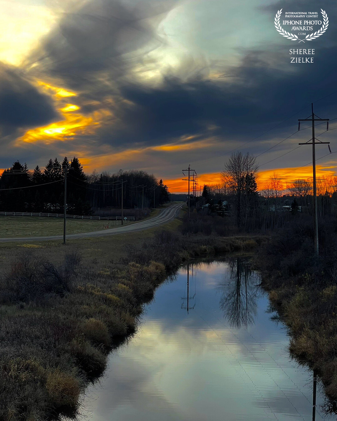 Near Sylvan Lake in our province of Alberta affords many photo opportunities, especially at sunset. But I had to chase this one to find a dramatic foreground subject. We found this ditch with its watery tree reflections down a gravel road. Perfect.