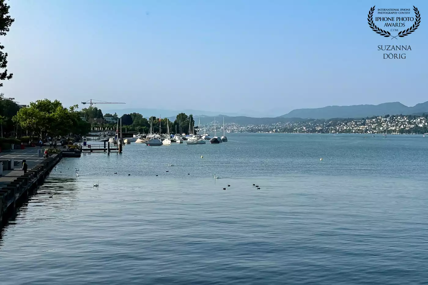This view early morning over the Lake of Zurich. Only few people are walking around and enjoy the early hour of the day. One of my favourite times as well to explore the city.